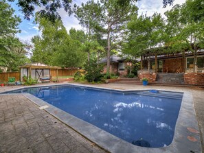 A rectangular swimming pool with a brick border, surrounded by a paved patio. - Ranchwood Manor Escape: Pool, Yard, Comfort in OKC (Oklahoma City)