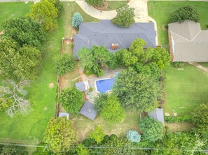 An aerial view of a residential property with a swimming pool, surrounded by trees and a well-maintained lawn. - Ranchwood Manor Escape: Pool, Yard, Comfort in OKC (Oklahoma City)