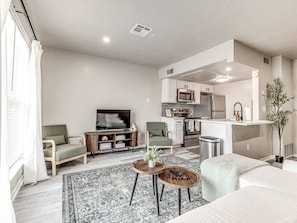 A modern living room with a sofa, armchairs, a coffee table, and a TV. - Lovely 1-Bedroom King Bed in Paseo (Oklahoma City)