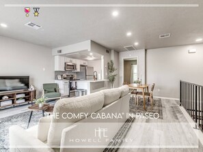 A spacious living area with a sofa, TV, and dining table. - Lovely 1-Bedroom King Bed in Paseo (Oklahoma City)
