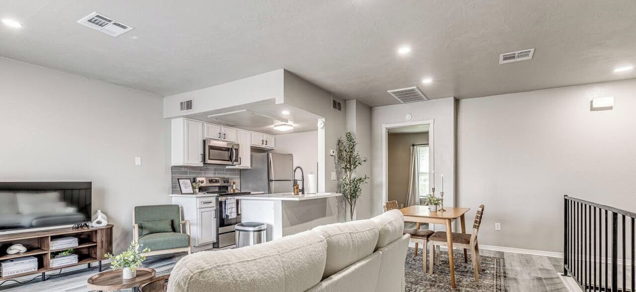 A modern living room with a sofa, TV, and a dining area with a table and chairs.