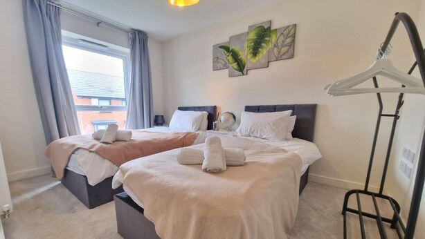 Une chambre d’hôtel avec deux lits, un luminaire suspendu, un globe terrestre fixé au mur et une fenêtre avec des rideaux.