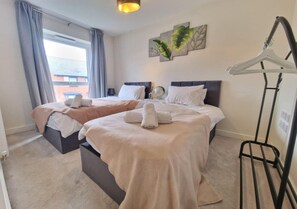 A hotel room with two beds, a hanging light fixture, a wall-mounted globe, and a window with curtains. - 3bedroom Near Nec & Airport W/parking and Garden (Birmingham)