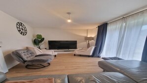 Un salon moderne avec un téléviseur à écran plat, deux canapés, une table basse et une plante en pot.