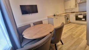 Une cuisine de taille réduite, équipée d’un évier, d’une cuisinière et d’un lave-linge.