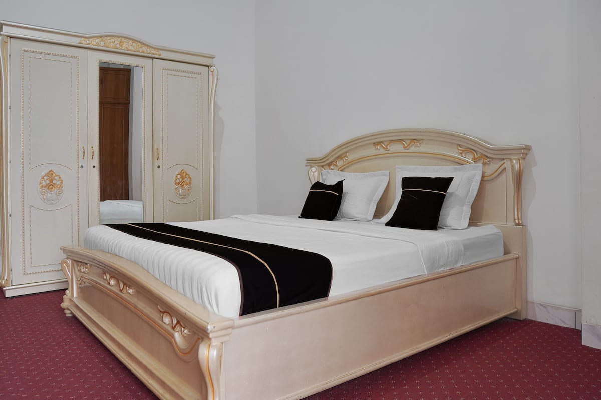 A bedroom with a bed, wardrobe, and a red carpet.