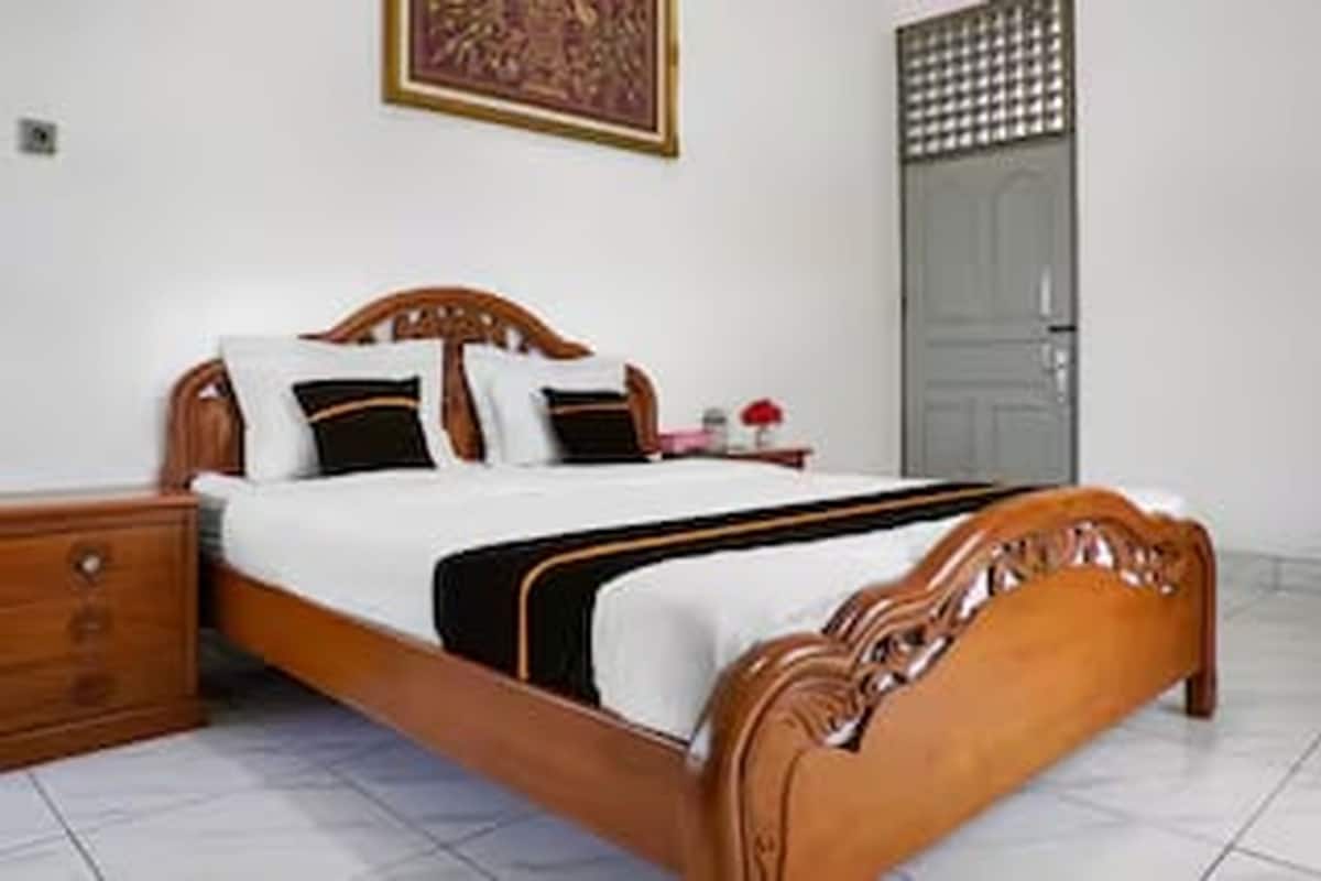 A neatly made bed with a wooden headboard, a nightstand, and a wall-mounted artwork.