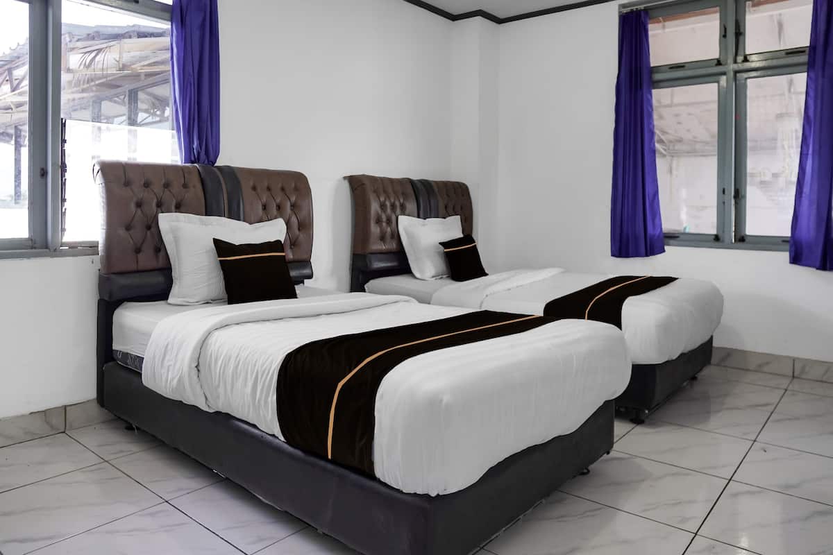 A double bed with a black frame and white bedding, two nightstands, and a window with blue curtains.
