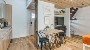 Una cocina moderna con armarios de madera, una mesa de comedor con sillas y una escalera que sube a un nivel superior.