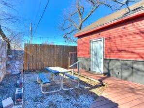 A backyard with a picnic table, a wooden deck, and a red building. - Modern Loft Apartment - Sleeps 4 (Oklahoma City)