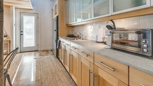 Una cocina moderna con armarios de madera, horno integrado y tostadora.