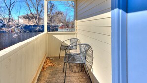 A covered porch with two metal chairs and a small table. - Updated Garage Apartment (Oklahoma City)