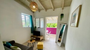 Una sala de estar moderna con un sofá, una mesita, un televisor y una lámpara colgante.