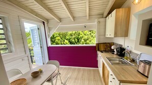 Una cocina compacta con vista por la ventana, un comedor con mesa y sillas, y un refrigerador pequeño.