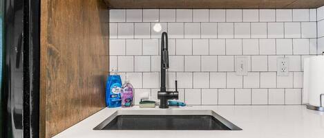 A kitchen with a sink, wooden countertop, and blue cabinets.