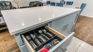A kitchen with a white countertop, blue cabinets, and a drawer organizer containing utensils. - Beautiful 2-Bedroom Near Wheeler (Oklahoma City)