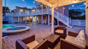 Un espace extérieur abrité, aménagé avec des meubles en osier, un jacuzzi et une piscine.