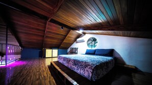 A bedroom with a wooden ceiling, a bed with a patterned bedspread, and a circular window. - Blu House Luxe: 6BR for Large Families, Jacuzzi and Panoramic Views (Provincia de Alajuela)