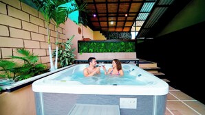 A couple in a hot tub with a brick wall and green plants in the background. - Blu House Luxe: 6BR for Large Families, Jacuzzi and Panoramic Views (Provincia de Alajuela)