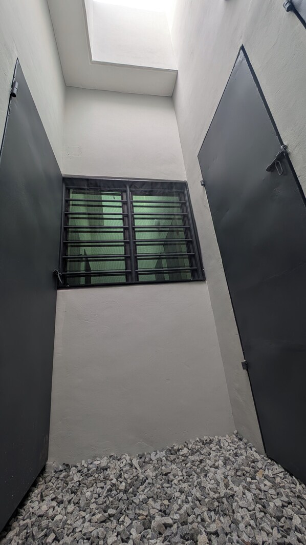A narrow corridor with a skylight above a window, flanked by two closed doors.