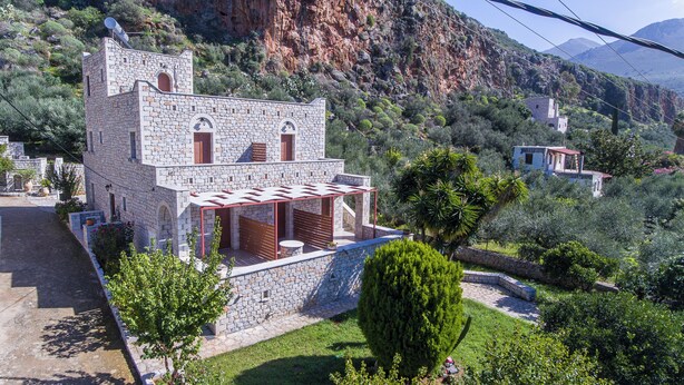 Ένα κτίριο από πέτρα με μπαλκόνι και θέα σε ένα ορεινό τοπίο.