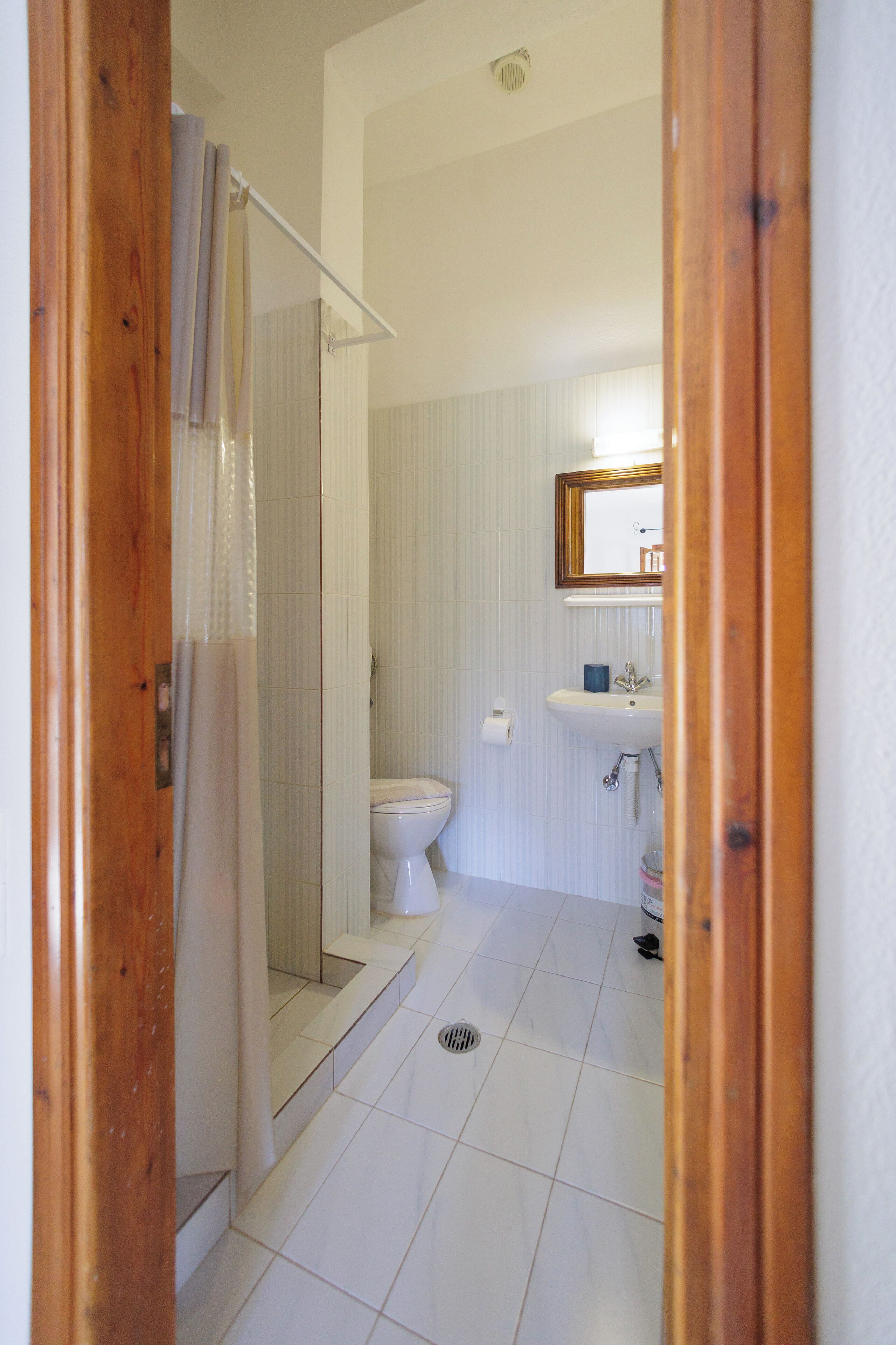 A bathroom with a shower, toilet, sink, and mirror.