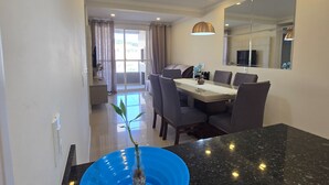 A dining area with a table and chairs, a large mirror, and a potted plant. - 3 minutes from the beach in the center of Bombinhas. Fully equipped apartment. (Bombinhas)