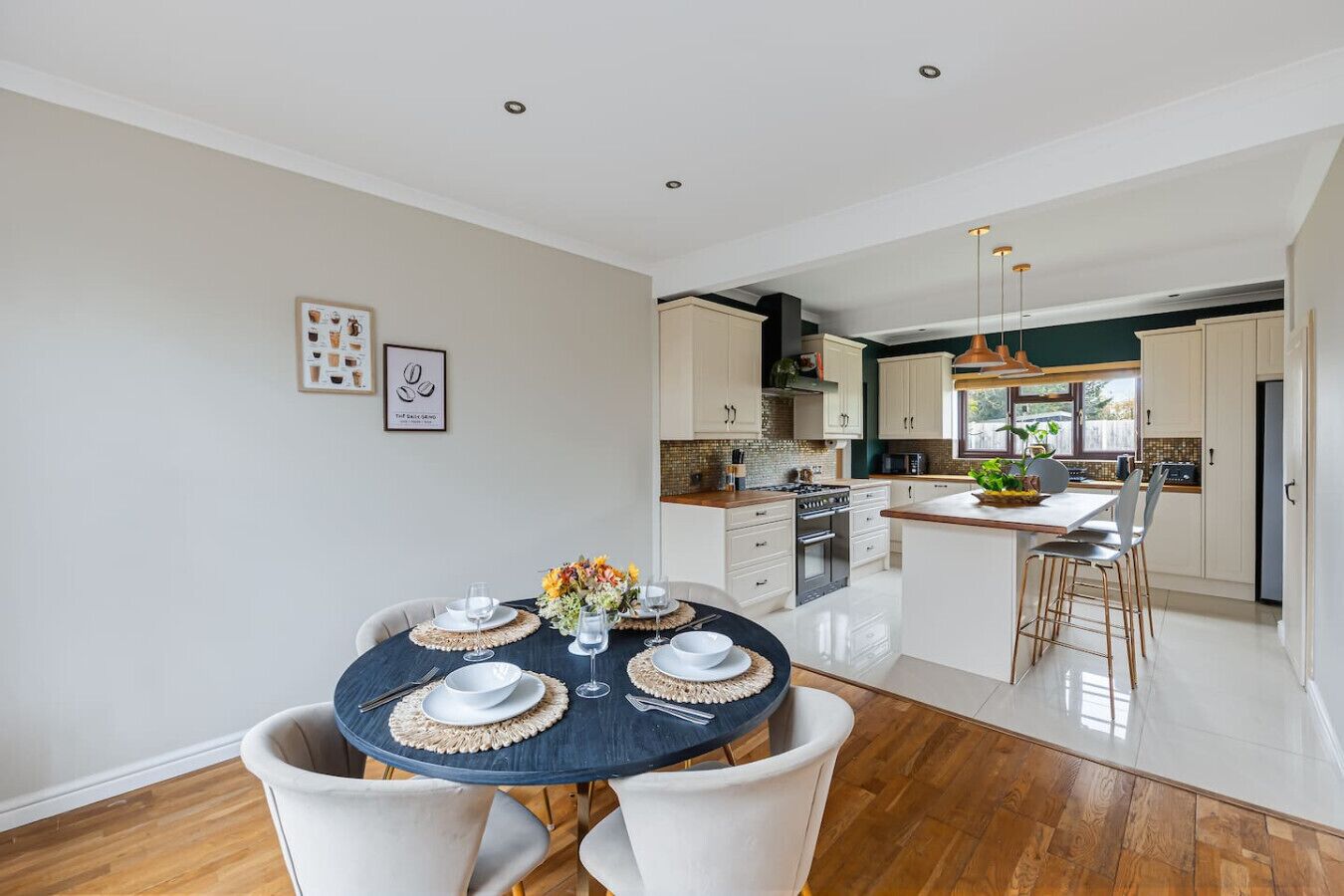 A modern kitchen with white cabinets, a central island, and a dining area with a round table set for four.