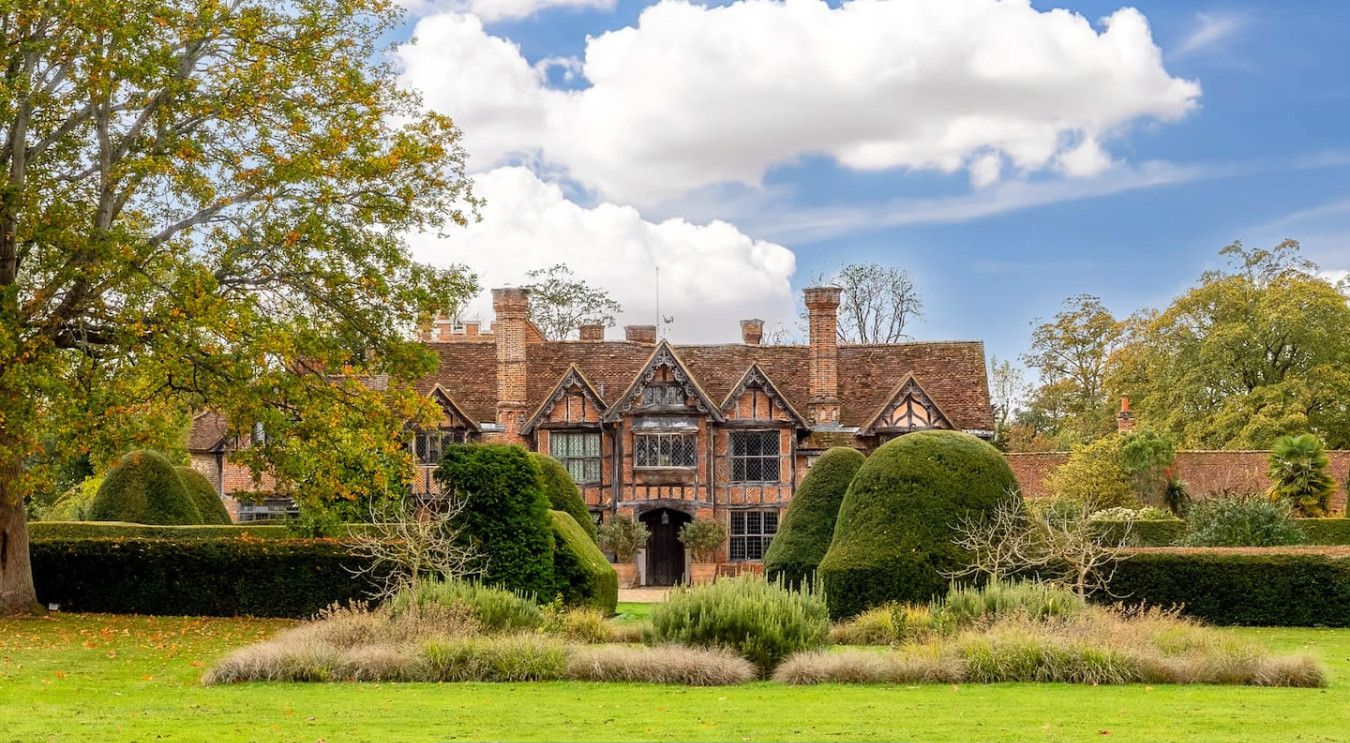 A historic building with a symmetrical facade, large windows, and a well-manicured garden.