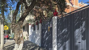 Ein geschlossenes Wohngebiet mit Baum, Straßenschild und Gebäude im Hintergrund.