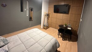 Una camera da letto con un letto, un tavolino con sedie, una TV a parete e uno specchio.