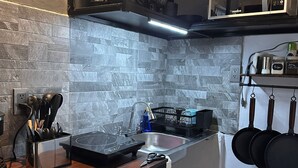 Una cucina compatta con rivestimento in pietra, piano cottura integrato, lavello e un piccolo angolo ristoro con una panca.