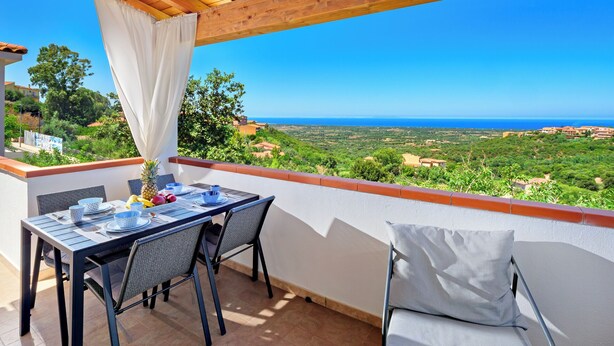 En balkon med et bord til to, med udsigt over et kystlandskab.