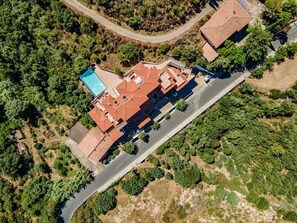 Ett flygbildsbild av en bostadsfastighet med en swimmingpool, flera byggnader och omgivande grönska.
