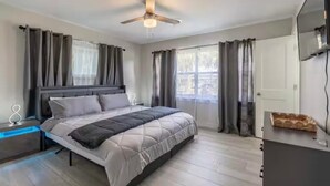 Ein modernes Schlafzimmer mit Bett, Deckenventilator und Nachttisch.