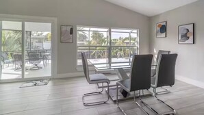 Ein moderner Besprechungsraum mit Glastisch und Stühlen, großen Fenstern mit Blick auf Palmen und Kunstwerken an den Wänden.