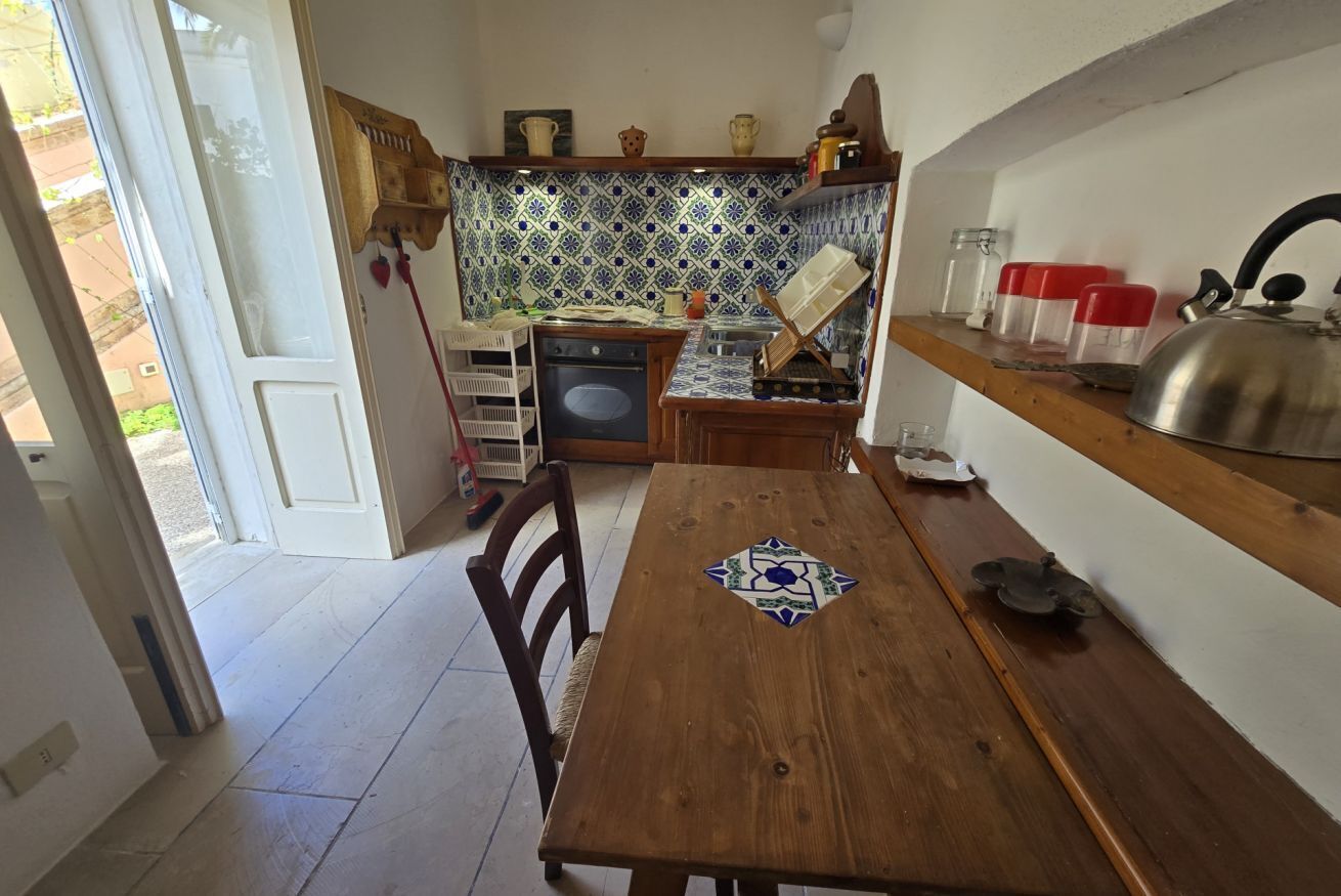 Una cocina con una mesa de madera, estufa y salpicadero de azulejos.