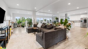 A spacious living area with a large grey sectional sofa, a flat-screen TV, and a kitchen in the background. - Spacious 4-bedroom house with fitness room, sauna, hot tub in vibrant Denver (Denver)