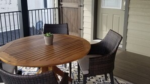 Een houten tafel met rieten stoelen, een plafondventilator en een kamerbreed tapijt op een balkon.