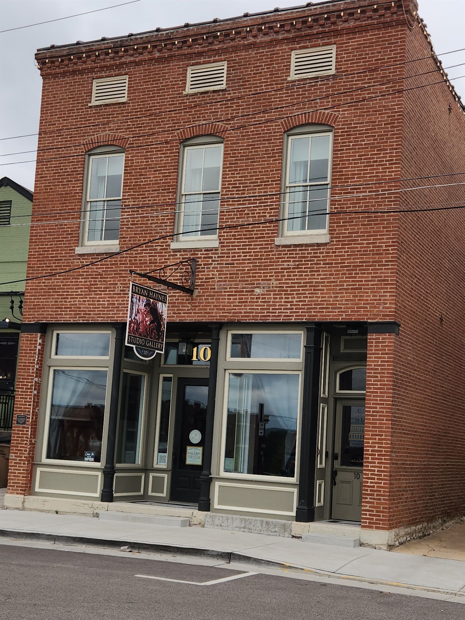 A brick building with large windows and a sign for a gallery.