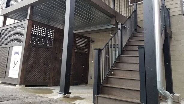 Een gebouw met twee verdiepingen, een balkon, een trap en een hekwerk.