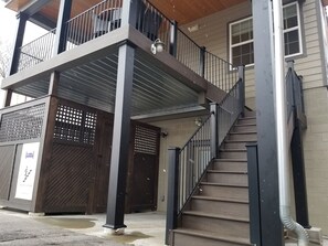 Un immeuble de deux étages doté d’un balcon, d’un escalier et d’une entrée fermée par un portail.