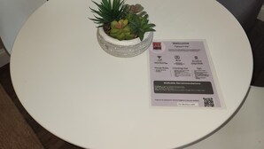 Een ronde witte tafel met een klein plantje en een welkomstkaart.