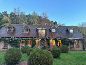 Ein traditionelles Backsteinhaus mit steilem Satteldach, zahlreichen Fenstern und einer großen Haustür.