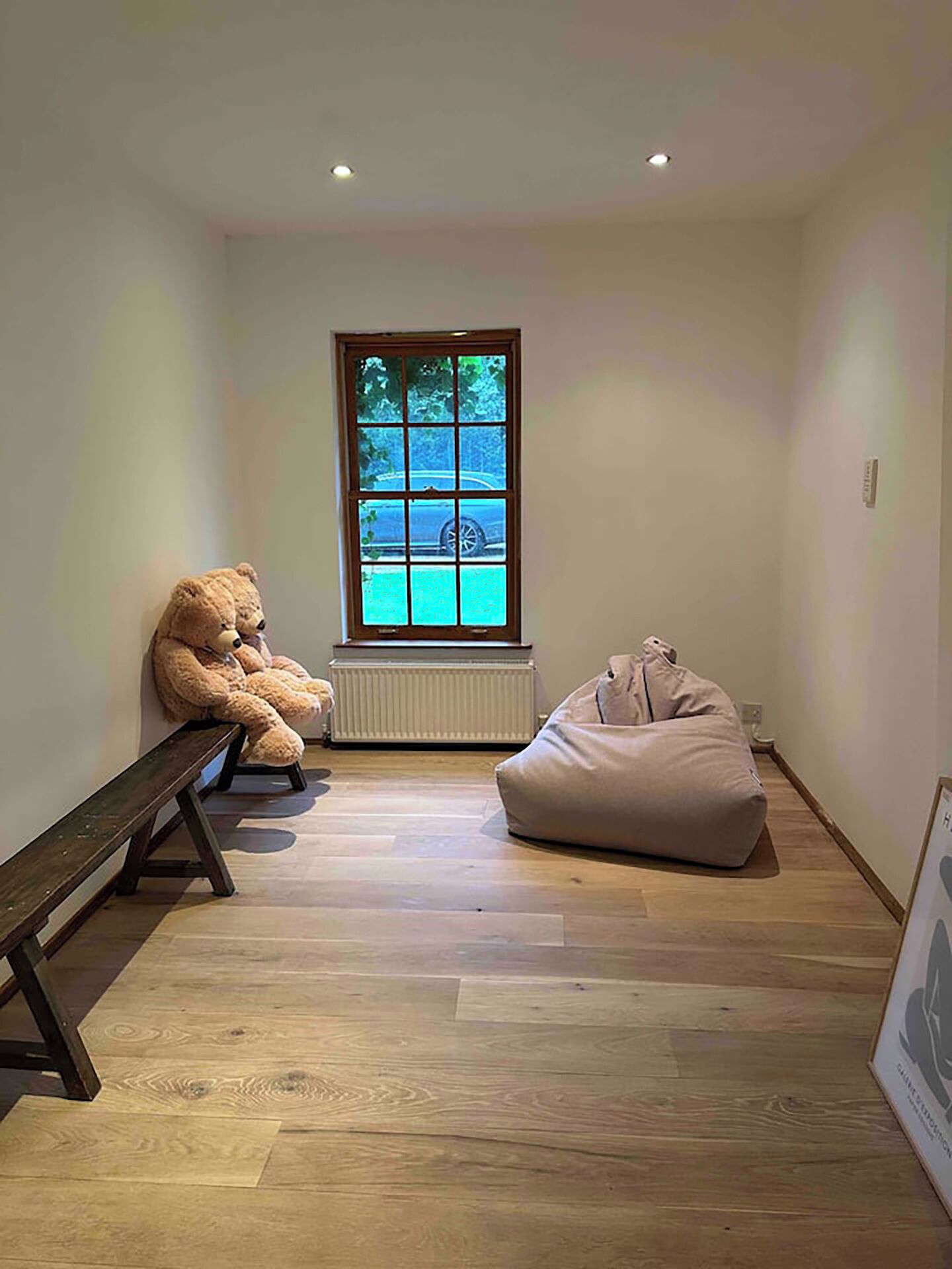 A room with a large window, a bench, and a bean bag chair.
