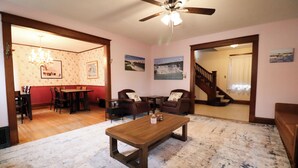 Un salón amplio con una mesa de centro de madera, sofás de cuero, una araña y una escalera que conduce a otra habitación.