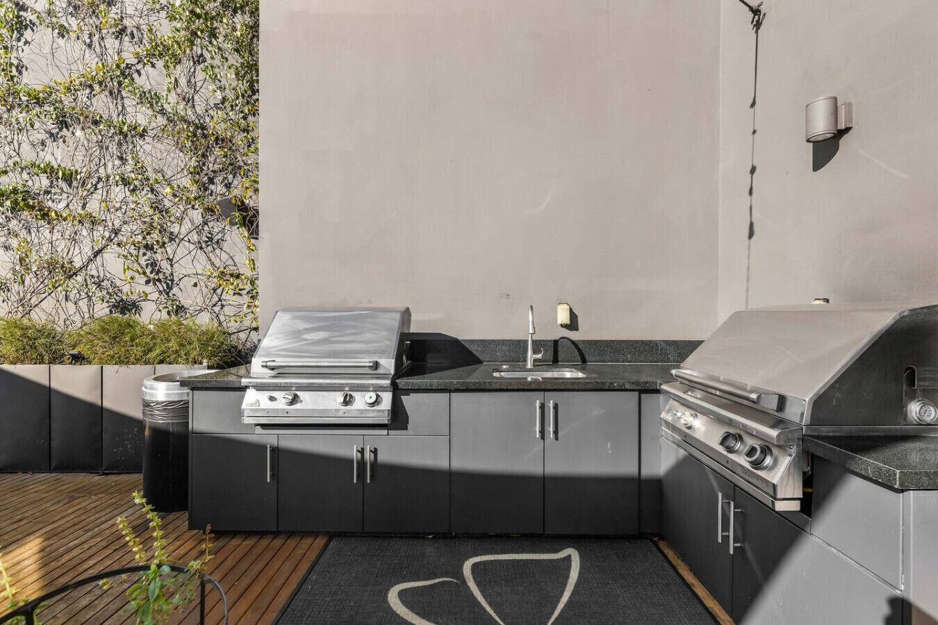 An outdoor kitchen with a built-in grill, a sink, and a countertop.