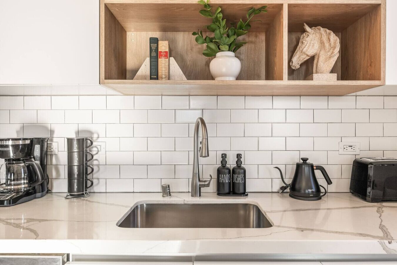A modern kitchen with a stainless steel sink, a coffee maker, a toaster, and a knife block.