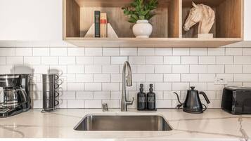 A modern kitchen with a stainless steel sink, a coffee maker, a toaster, and a knife block.