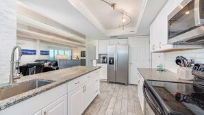 A modern kitchen with white cabinetry, granite countertops, stainless steel appliances, and a black stove. - Salt Life Oasis - Direct Oceanfront, End Unit in Satellite Beach, FL (Satellite Beach)